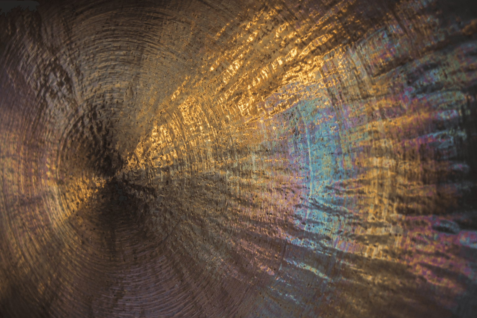 Close-up of a gong surface with gold and rainbow reflections